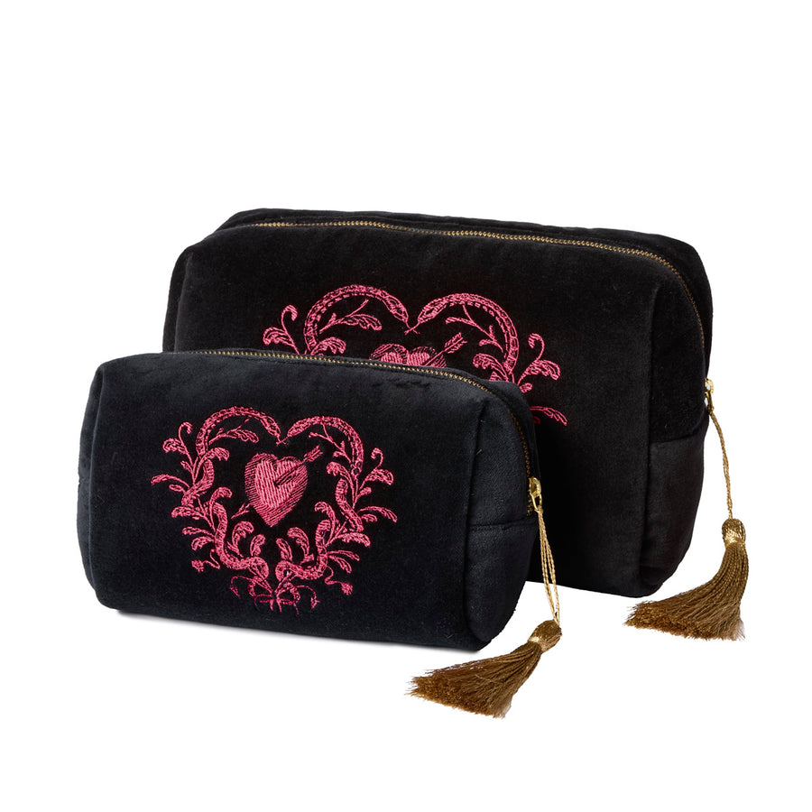 Two black velvet pouches with pink heart designs with snakes and gold tassels on a white background