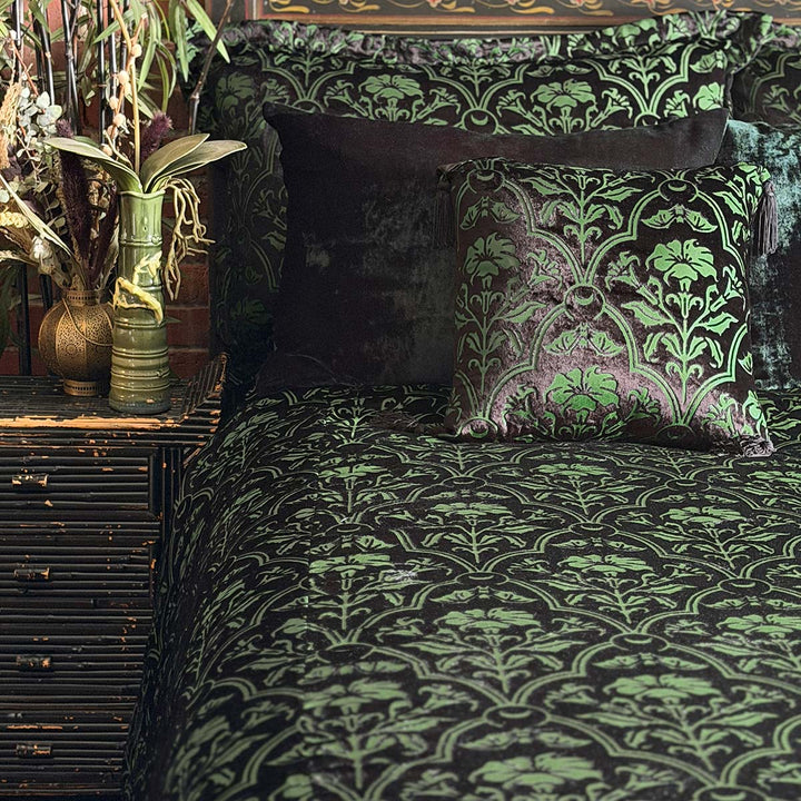 Sin in Linen's Velvet Datura bedding collection on a bed. Green gothic botanical pattern featuring datura blooms and bats in a flocked velvet design. Dark, witchy decor. 