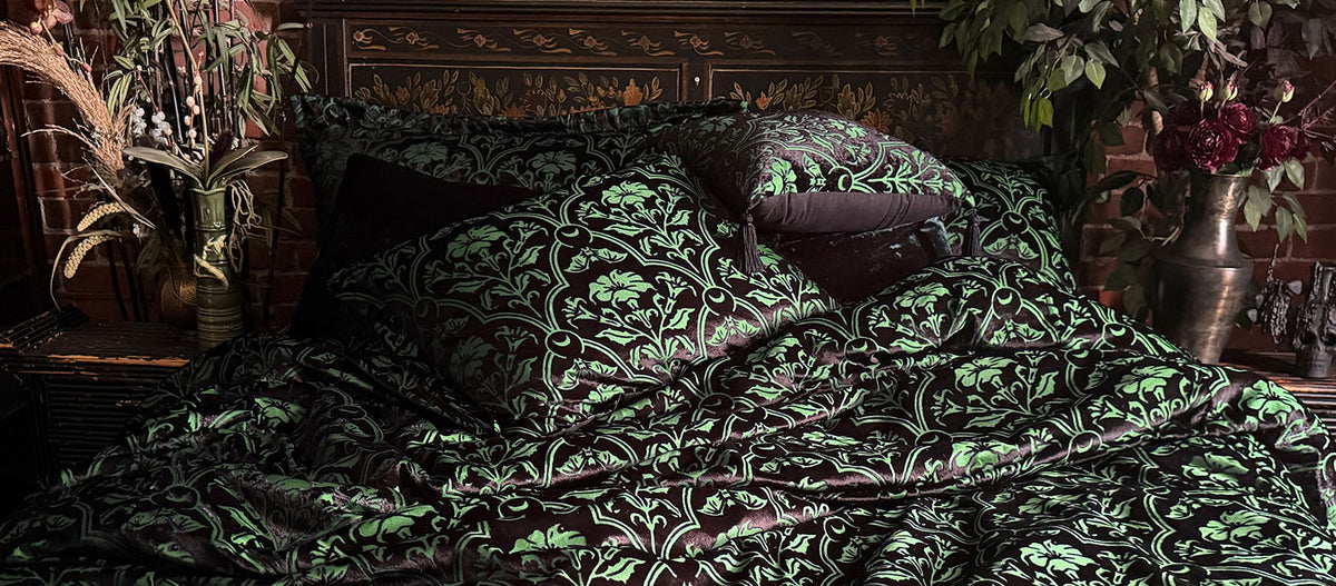 Sin in Linen's Velvet Datura Deco Bedding collection with a shapeshifting green hue and black flocked velvet. Mysterious, dark & gothic decor. The pattern features datura blooms, moons, and bats. 