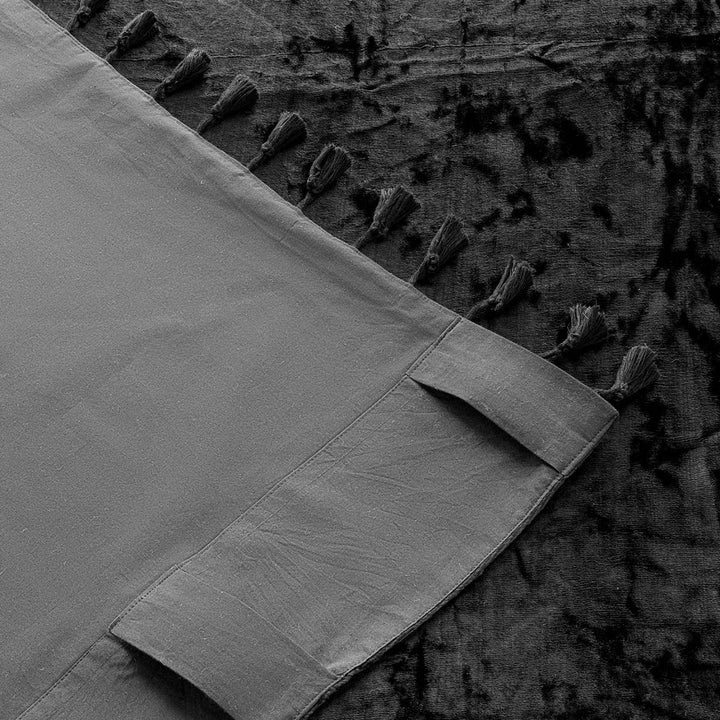 Black tasseled velvet curtain with a cotton backing. Image shows the corner of the curtain turned over to see the back. 