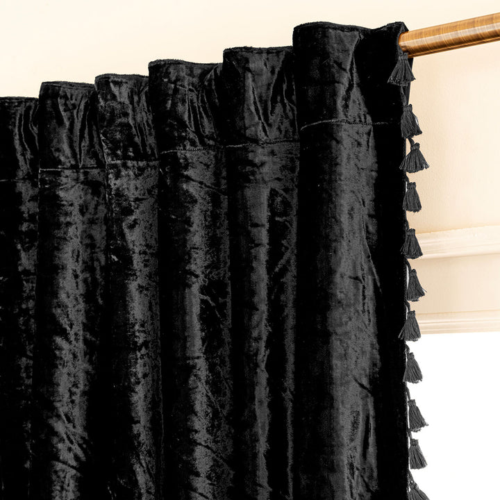 Black velvet curtain with tassels on rod by a window