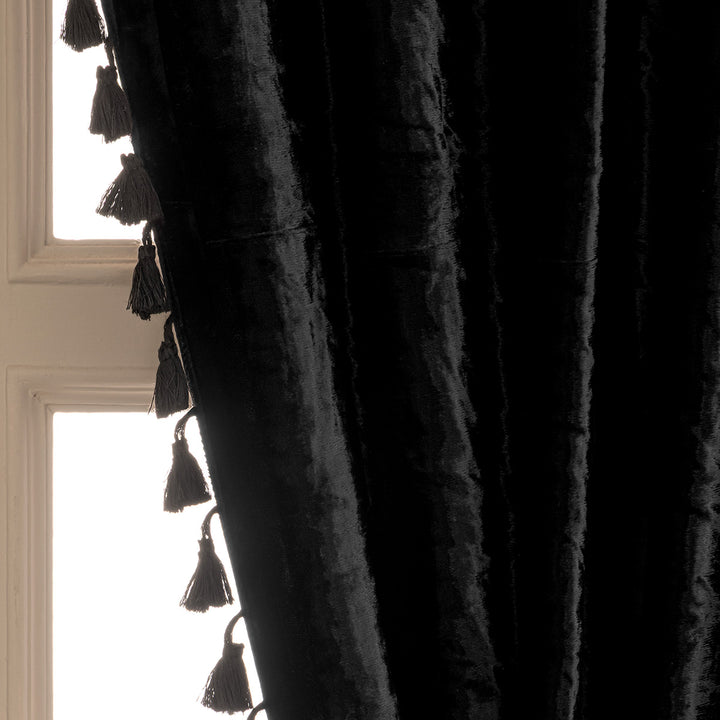 Black tasseled curtain against a window