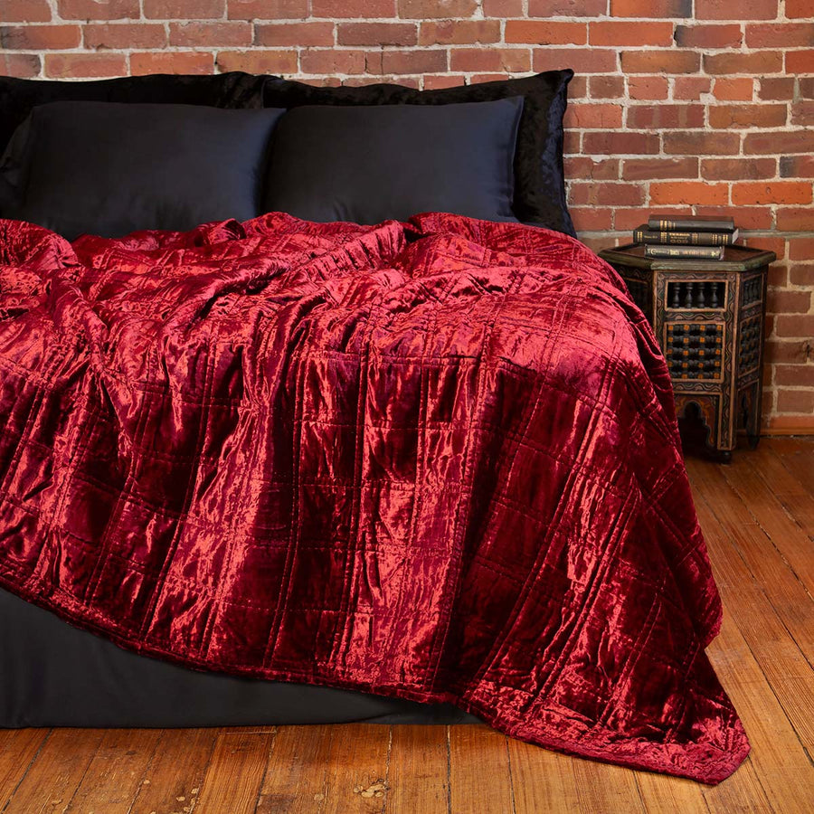 Red velvet box quilt on bed. Dark, alternative velvet bedding. 