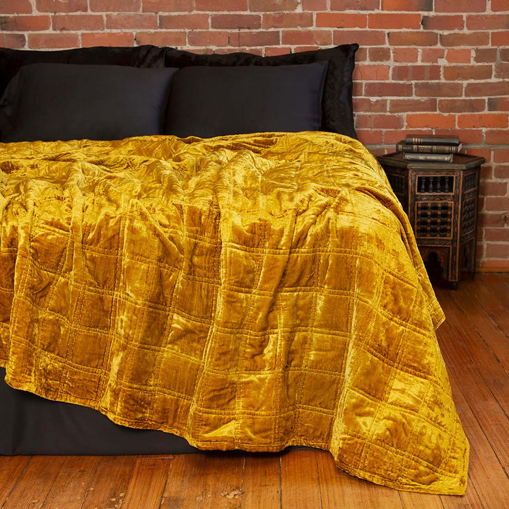Gold velvet box quilt on a bed. Bohemian, witchy velvet decor. 