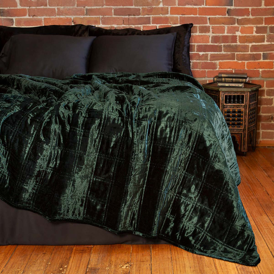 Forest green velvet box quilt on a bed. Dark, moody velvet bedding. 