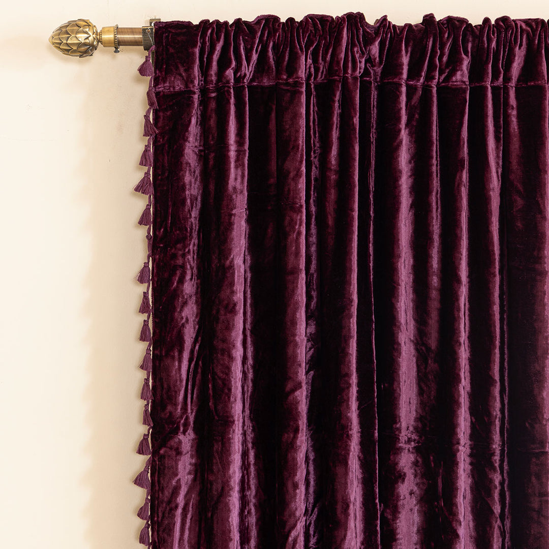 Purple velvet curtain with a decorative rod on a white wall