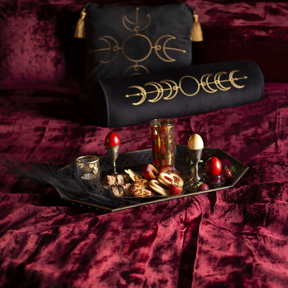 Ruby red velvet bedding with celestial velvet pillows and a tray of fruit. 
