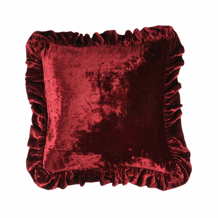 Red velvet pillow with ruffled edges on a white background
