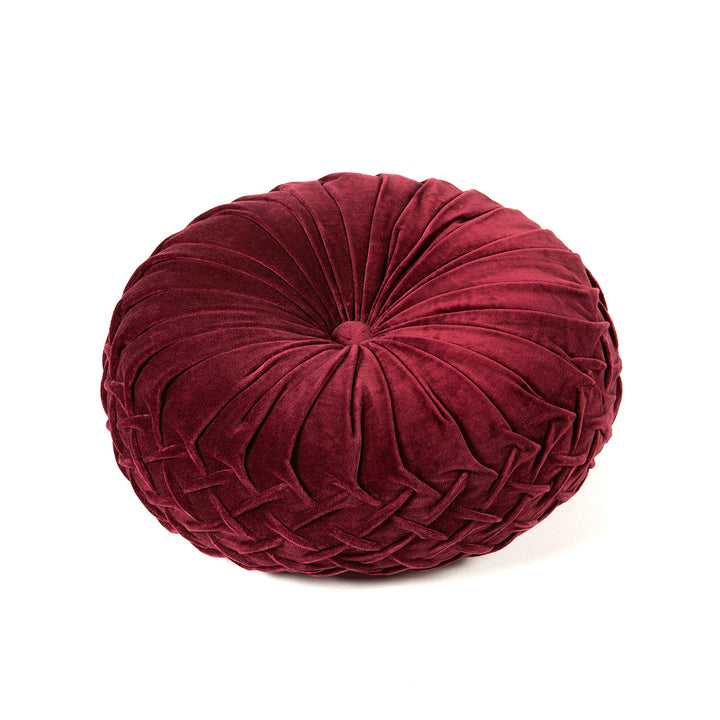 Round, burgundy velvet pillow on a white background