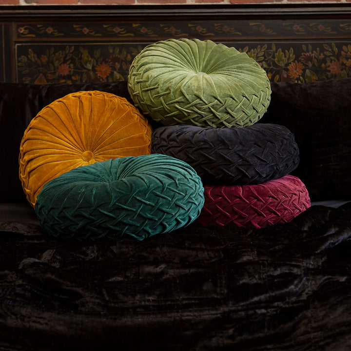 A pile of five velvet pintuck pillows in black, gold, ruby red, moss green, and forest green. Luxurious throw pillows by Sin in Linen on a bed of black velvet bedding. 