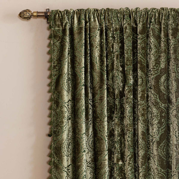 Moss green damask velvet curtain on a curtain rod. 