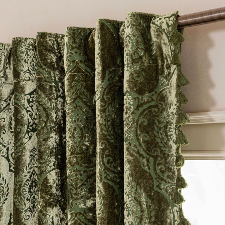 Moss green damask velvet curtain with tassels on a curtain rod showing the tab hanging method.