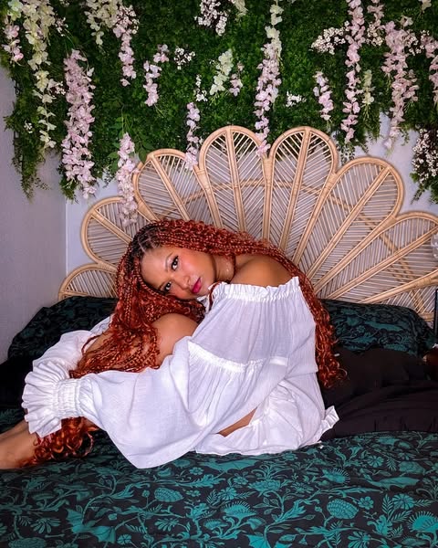 Woman in a white off-shoulder top lying on a green and black botanical sheet set. Green Elysian Fields by Sin in Linen