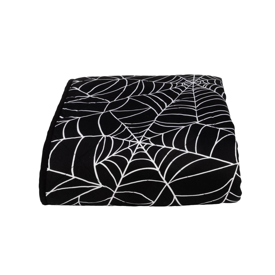 A folded black and white spider web throw blanket on a white background.