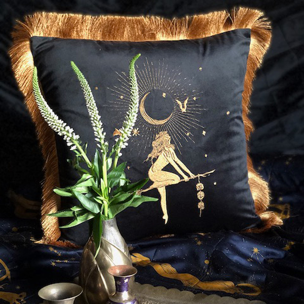 Velvet embroidered pillow featuring a witch on a broom stick next to a crescent moon